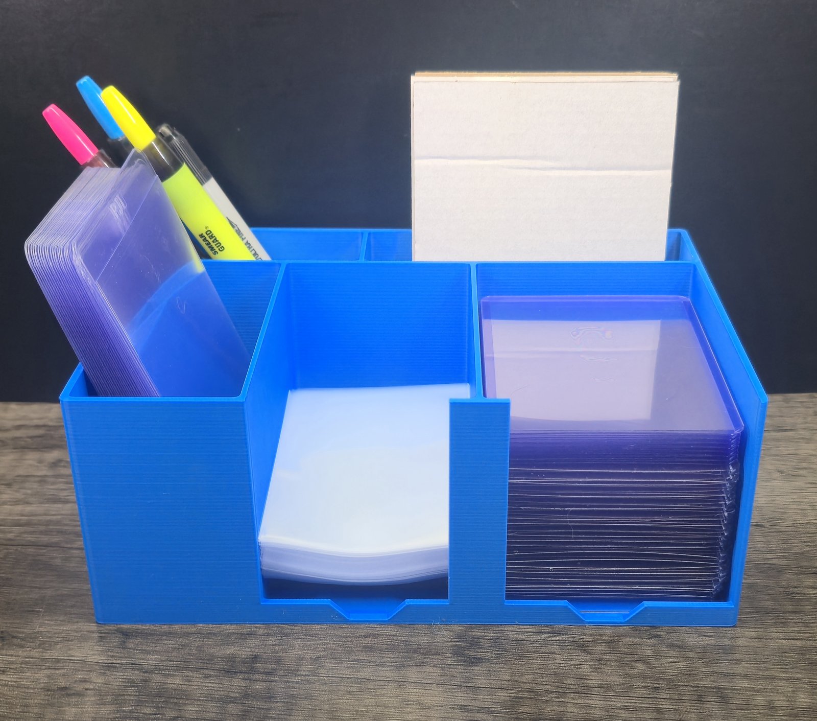 A blue Card Packing Station Organizer loaded with toploaders, sharpies, and cards