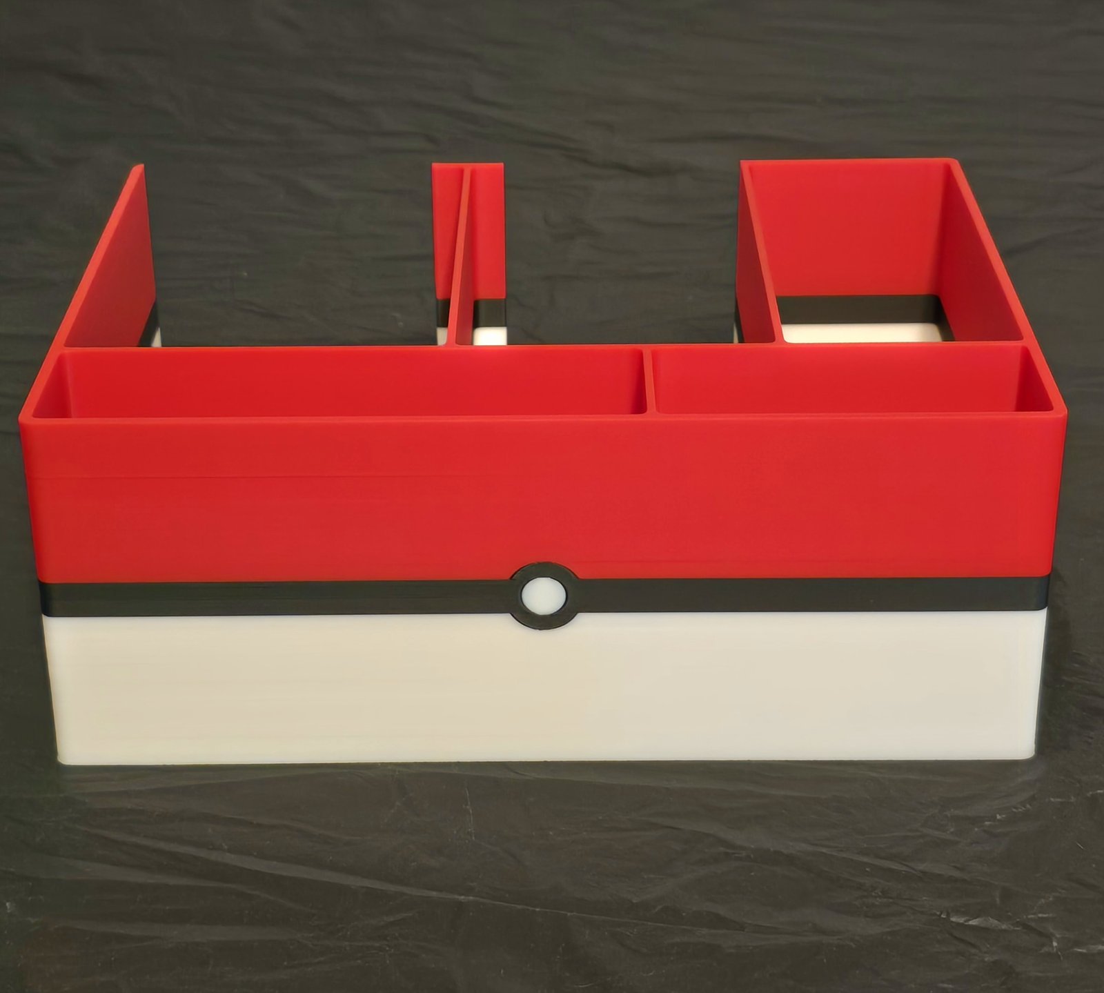 The Poké Ball Rip and Packing Station in red, white, and black with a black band and white button on the front
